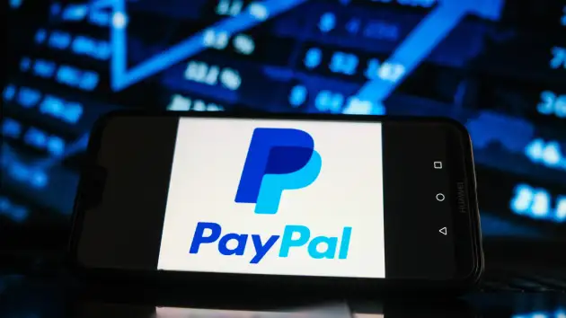 Logo PayPal hiển thị trên màn hình điện thoại thông minh với đồ họa thị trường chứng khoán ở nền